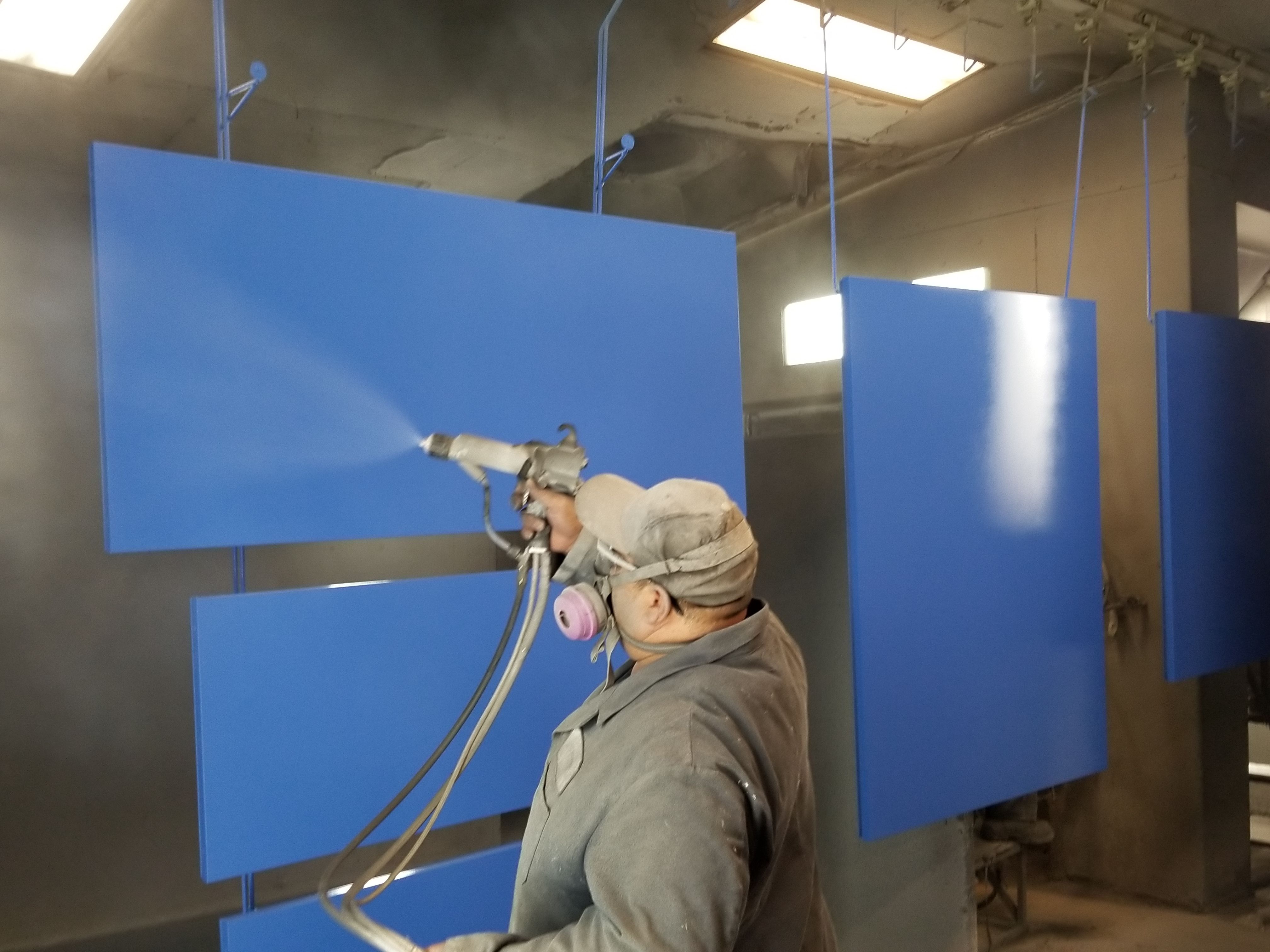 A member from the Certified Enameling, Inc. team coating panels blue